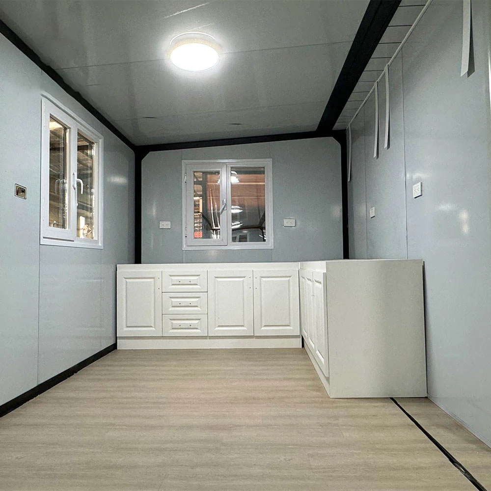 Container home shell interior — white kitchen cabinets, light wood-effect floor, fitted ceiling panels and windows